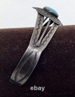 A vintage Fred Harvey sterling silver bracelet with a turquoise cabochon center